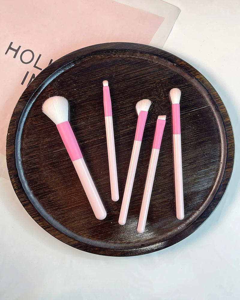 Five-piece pink makeup brush set on a dark tray