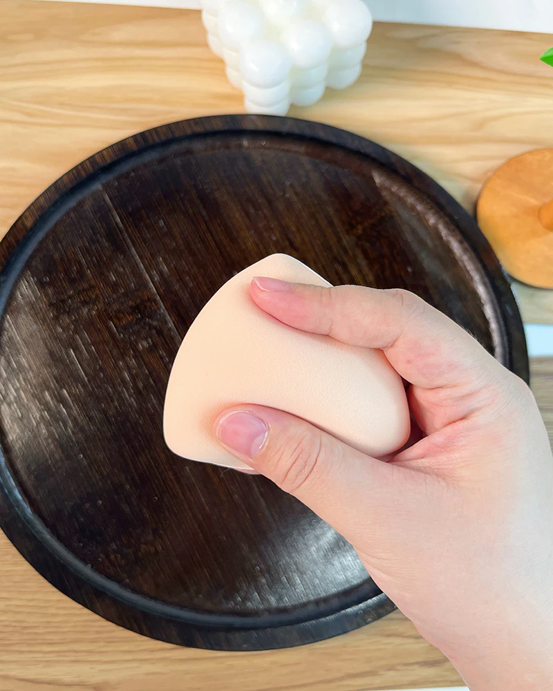 Soft triangular makeup puff compressed by hand